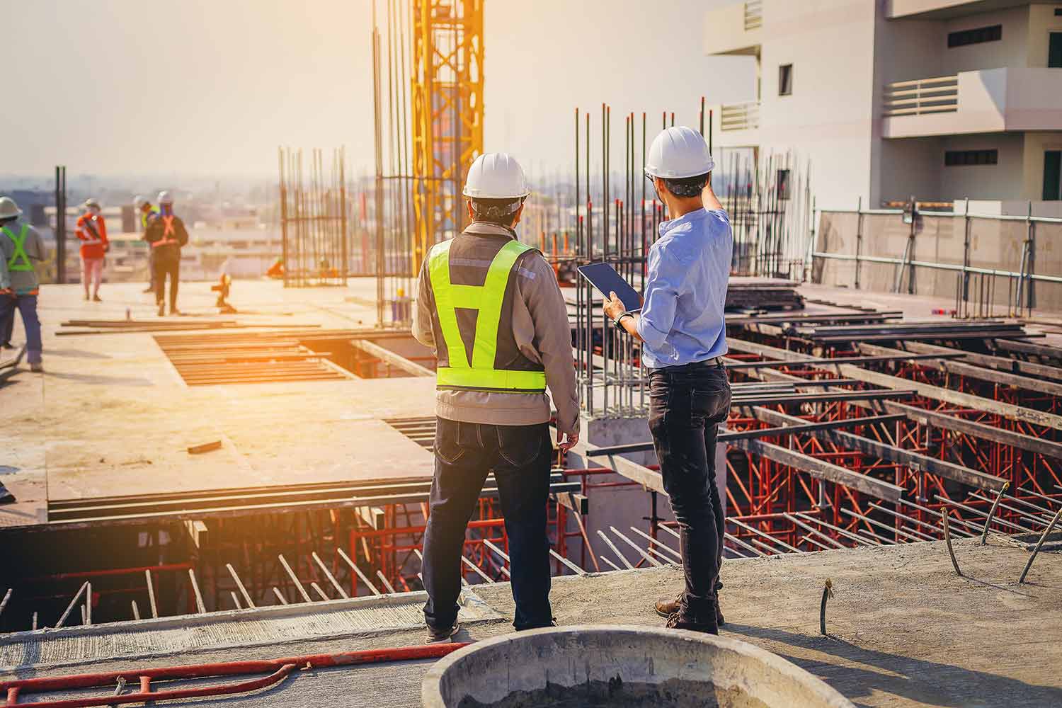 Bauingenieur und Bauarbeiter sprechen über baubegleitendes Facility Management.