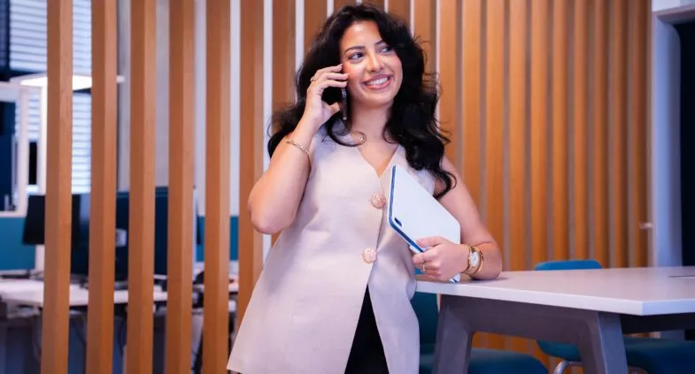 Junge Dame telefoniert und hält ein Notizbuch hin der Hand.