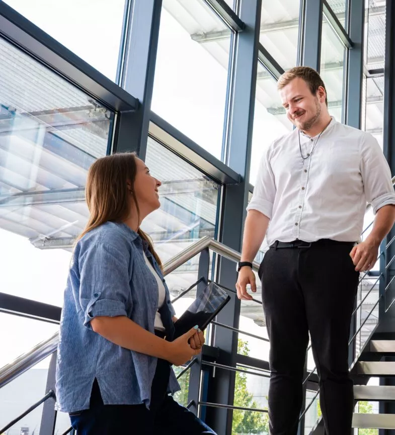 Zwei Kollegen schauen sich an und lachen dabei.